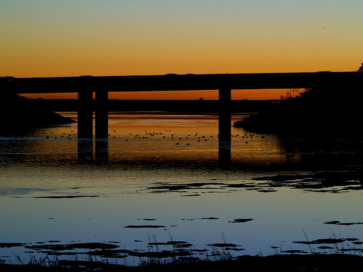 view of bridge over lagoon at sunset